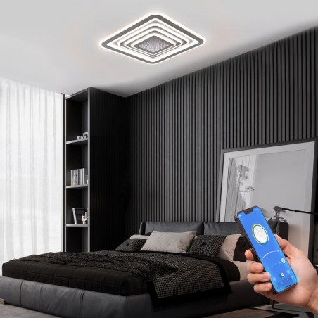 Dormitorio moderno decorado con Plafón Smart Otie 2 encendido y controlado con un móvil con iluminación combinada en tono neutro