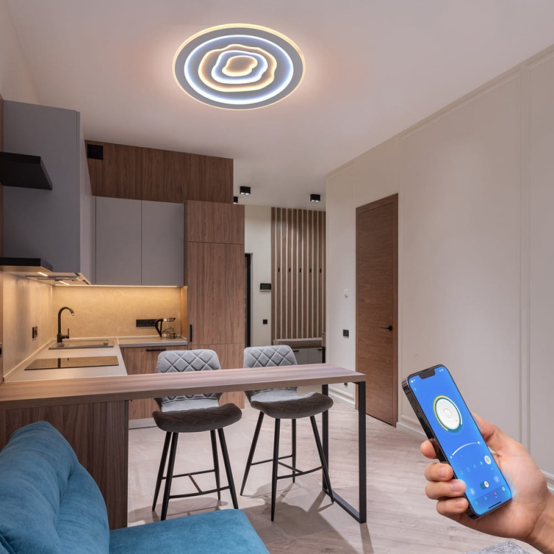 Cocina - comedor decorada con Plafón Smart Cloud encendido con iluminación combinada de tono cálido y controlado desde un móvil